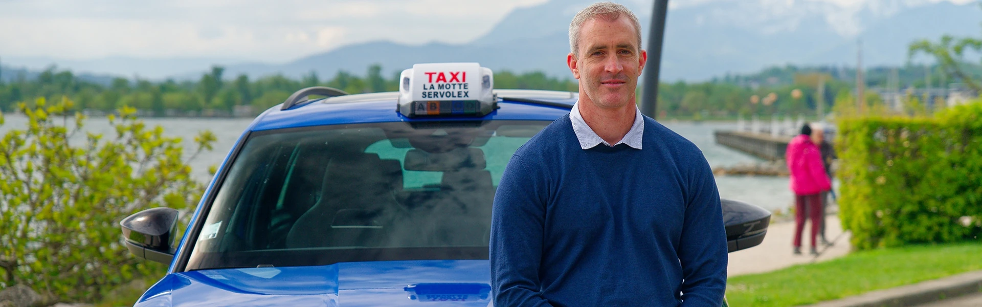 Chauffeur devant son taxi stationné au bord du lac du Bourget